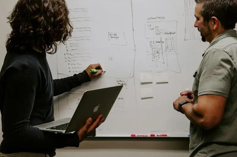 Two colleagues planning employee benefits at a whiteboard